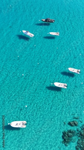 Bateaux au mouillage dans les eaux turquoise et peu profondes de la baie de Santa Giulia en Corse, vus du ciel.