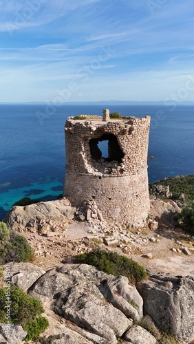 Tour génoise de Roccapina en Corse, bâtie en pierre sur un promontoire rocheux, surplombant la mer Méditerranée aux eaux limpides.