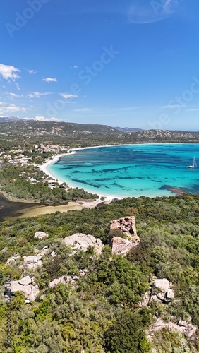 Vue aérienne de la baie de Saint Cyprien en Corse, avec ses eaux turquoise, sa plage et les ruines d’une tour génoise au premier plan.