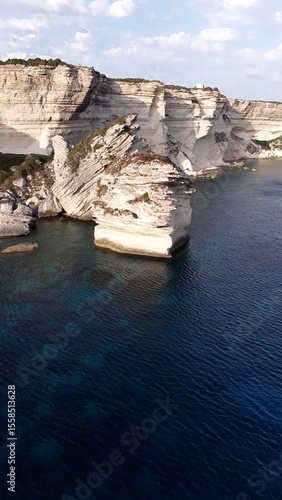 Falaises blanches et grain de sable de Bonifacio plongeant dans la mer méditerranéen, photographiées en hauteur par une lumière de fin d’après-midi.