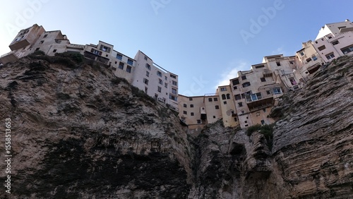 Maisons de Bonifacio construites au bord des falaises calcaires, vue depuis le bas montrant la hauteur et les détails architecturaux.