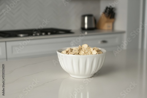 Wooden Kitchen Table with White Bowl of Raw Oats in Modern Kitchen Setting Featuring Sleek Design Elements and Clean Lines for Minimalist Appeal