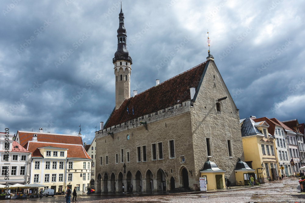 Obraz premium Tallinn Town Hall with medieval Gothic architecture and high spire in Old Town square, Estonia, captured with dramatic cloudy sky.