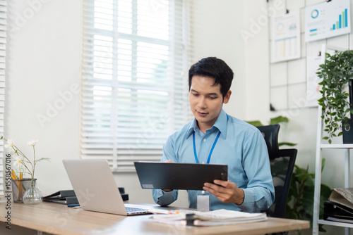 Remote Work and Productivity. Young businessman reviewing documents at modern office desk.
