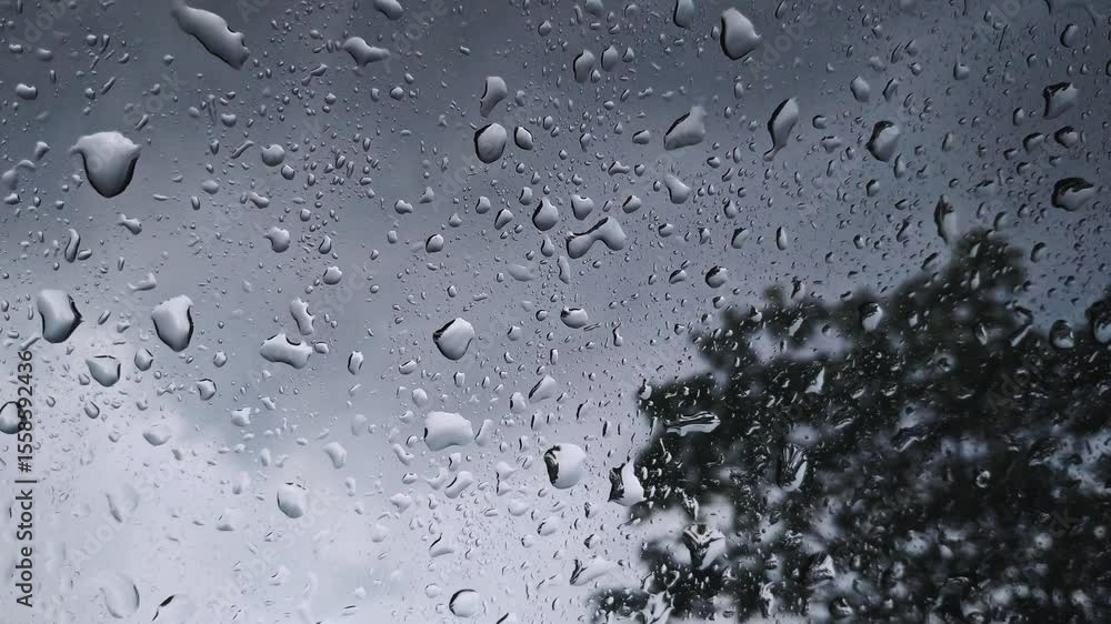 Rainwater running down a car windshield during a rainy day. The blurred background and water droplets create a moody scene. Stormy weather. Rainwater running down a car windshield during a rainy day. The blurred background and water droplets create a moody scene. Stormy weather.