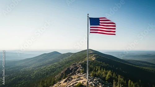 American flag waving on a mountain peak with a vast wilderness landscape view.