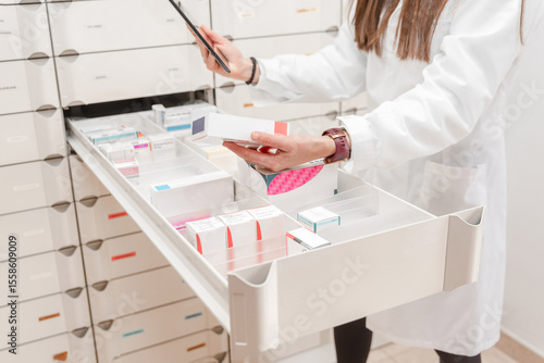 Close up of female Pharmacist scanning and organizing medicine boxes in drawer at pharmacy storage