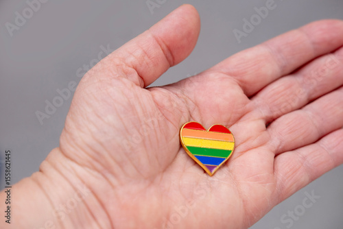 Wallpaper Mural Hand holding rainbow heart pin, representing love, diversity, and equality, solidarity and support for LGBTQ+ community, vibrant colors and clear symbolism, accessory jewelry Torontodigital.ca