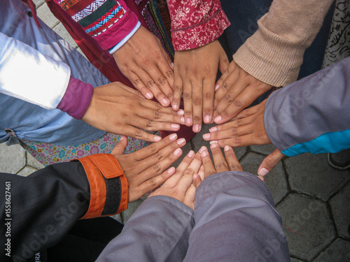 Wallpaper Mural Eight hands, each wearing a different colored long-sleeve shirt, are positioned together in a team huddle, facing downwards. Represents teamwork, collaboration, unity, diversity, and support Torontodigital.ca