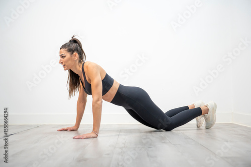 Athletic woman in plank position on knees preparing to start push-up exercise