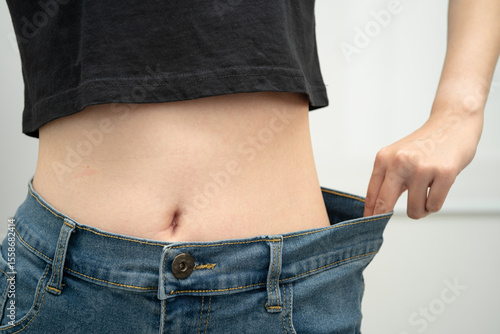 Foto Young Asian woman losing weight wearing loose pants in oversize jeans