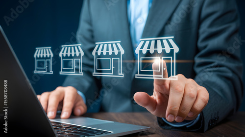 Businessman touching virtual shop icons on a laptop display, representing franchise business expansion and investment opportunities in retail.