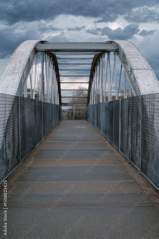 Fototapeta premium Arched Metal Bridge in an Industrial Area on a Cloudy Day