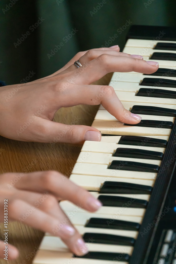 Obraz premium Fingers dancing effortlessly over the keys of an electronic keyboard, creating a captivating melody filled with skill and passion, embodying the essence of musical artistry. Vertical photo