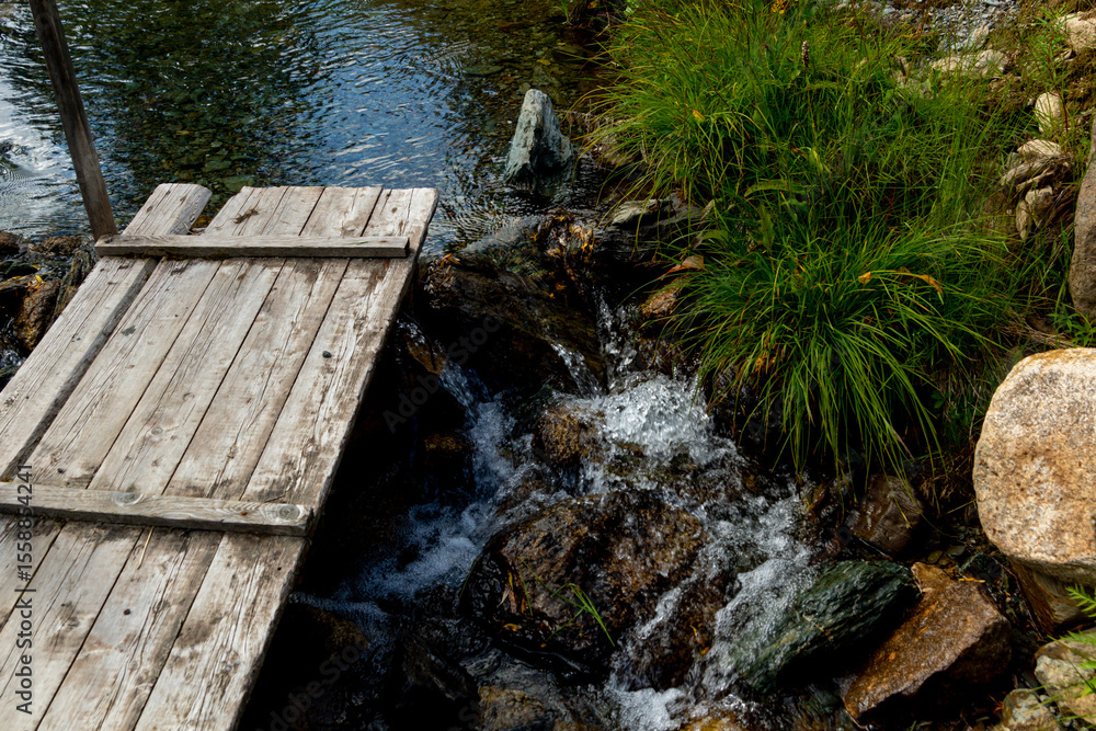 Obraz premium Wooden deck by a mountain stream