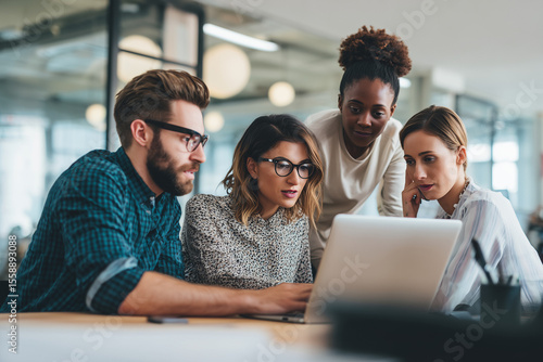 Diverse business team collaborating around a laptop in a modern office