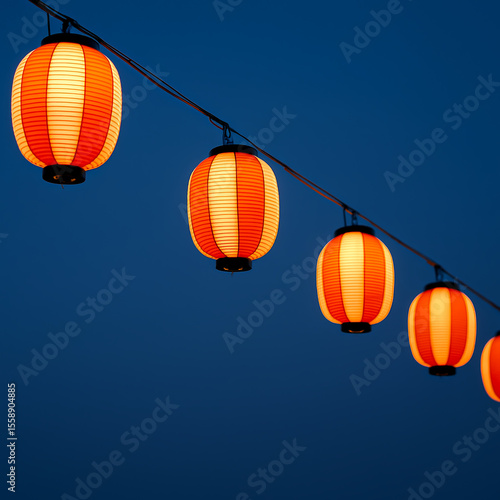 Row of glowing orange Japanese paper lanterns hanging against deep blue evening sky, summer festival ambience
