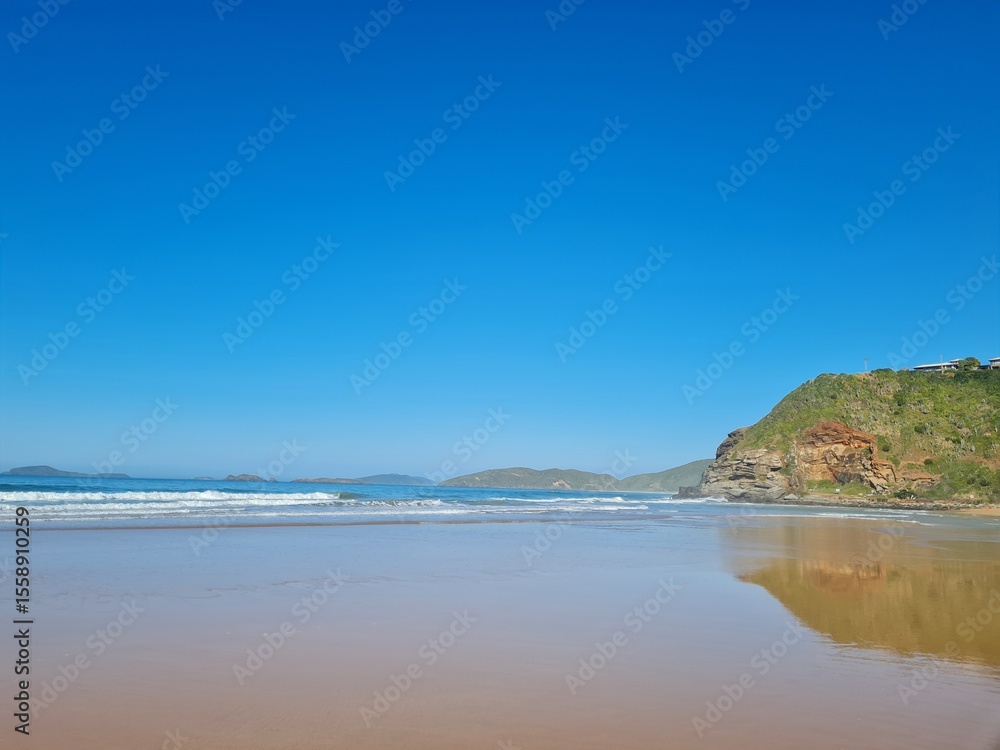 Fototapeta premium Sunny day at Geribá Beach, Búzios, Brazil. Golden sand, crystal clear water, strong waves, vibrant blue sky. Tropical paradise, serene landscape, summer vibe during Brazilian winter.