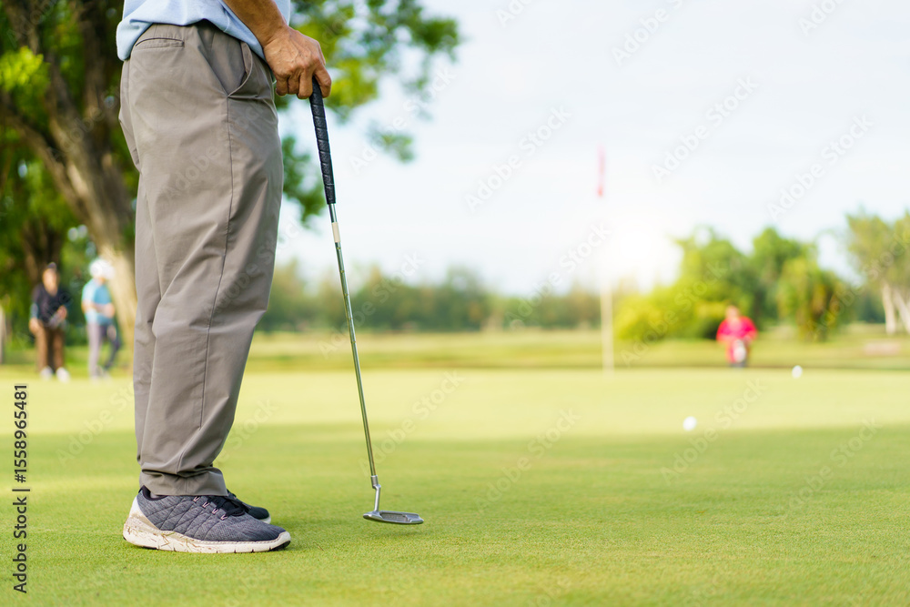 Fototapeta premium Elderly Asian man enjoying the morning round of golf in soft and warm sunlight.