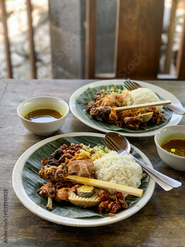 Nasi Campur is a Traditional Balinese rice dish served on a banana leaf with various side dishes, showcasing authentic Indonesian cuisine.