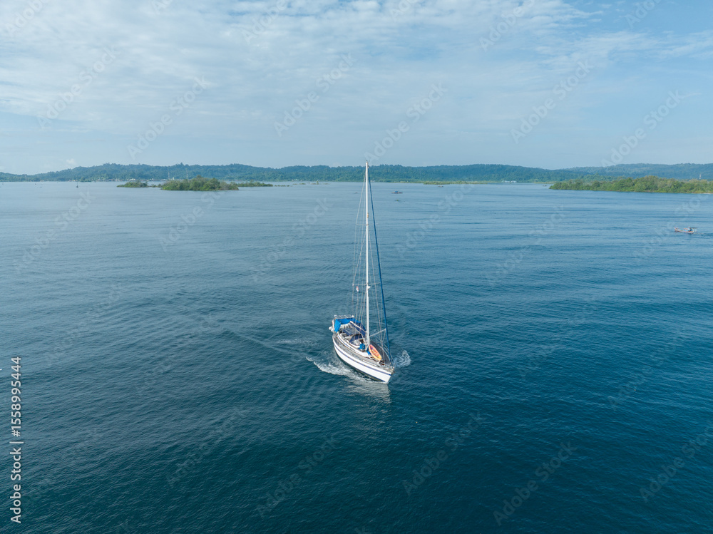 Fototapeta premium Aerial view of a sailboat cruising in the tropical island of Indonesia