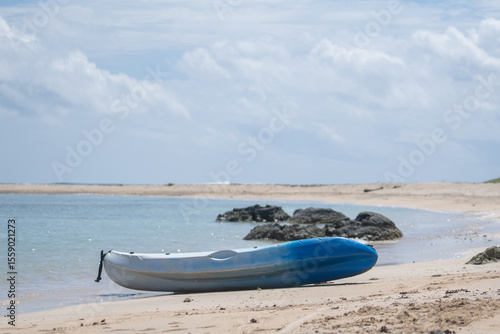 A small kayak sits on a tropical beach