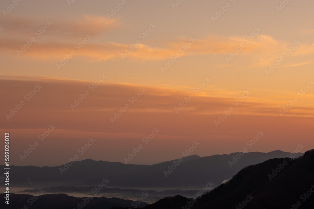 Obraz premium 埼玉県秩父市の三峰神社から望む朝焼けの山並みと空の風景。2022年11月19日撮影。晩秋の澄んだ空気の中、赤く染まった空と重なる山々が幻想的な絶景を描き、旅行や自然風景、癒しをテーマに最適です。