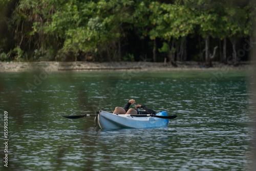 A man rests on a kayak in the middle of calm water