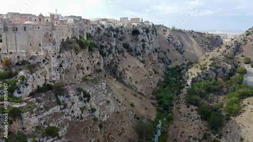 Aerial footage of Matera, a UNESCO-listed city in Basilicata, Italy, showing the ancient Sassi cave dwellings, rocky cliffs, and surrounding rural landscape under natural light.