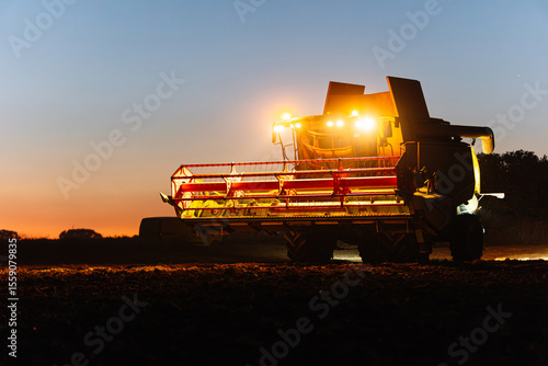 Tableau sur toile Combine harvester harvesting wheat at sunset