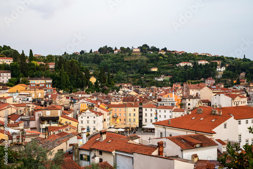 charming coastal town with red rooftops and colorful buildings surrounded by lush green hills. Piran old town, Slovenia 
