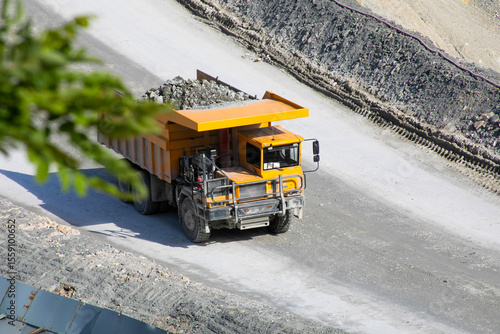 Titanic quarry truck trundles along dusty path, echoing Labor Days industrial spirit, embracing rock-laden journeys and iron behemoth nostalgia