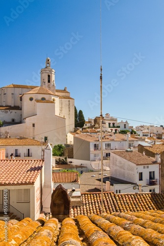 Charming narrow streets of Cadaqués, Spain, with white church on the hill, houses and vibrant blue sky, showcasing the historic Mediterranean coastal town’s beauty and traditional architecture