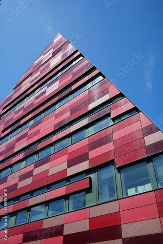 Nottingham, England - June 20 2025: Modern building with a striking red, pink, and maroon facade and long, narrow windows in a grid-like pattern.