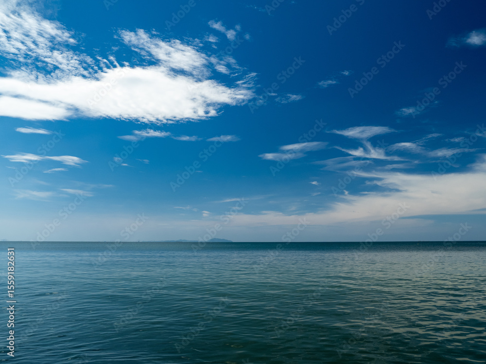 Obraz premium Serene tropical beach with crystal clear turquoise water, gentle waves, and a bright blue sky with fluffy white clouds. peaceful and relaxing summer scene perfect for panorama and travel concepts.