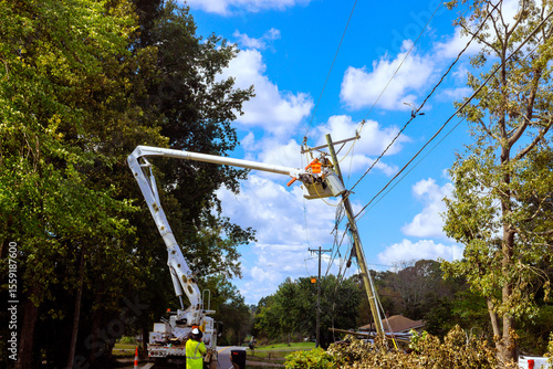 Fotografi Utility crew operates cherry picker to restore power lines in neighborhood affected by inclement weather conditions