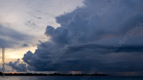 The sun is peeking through the cumulus clouds above the ocean