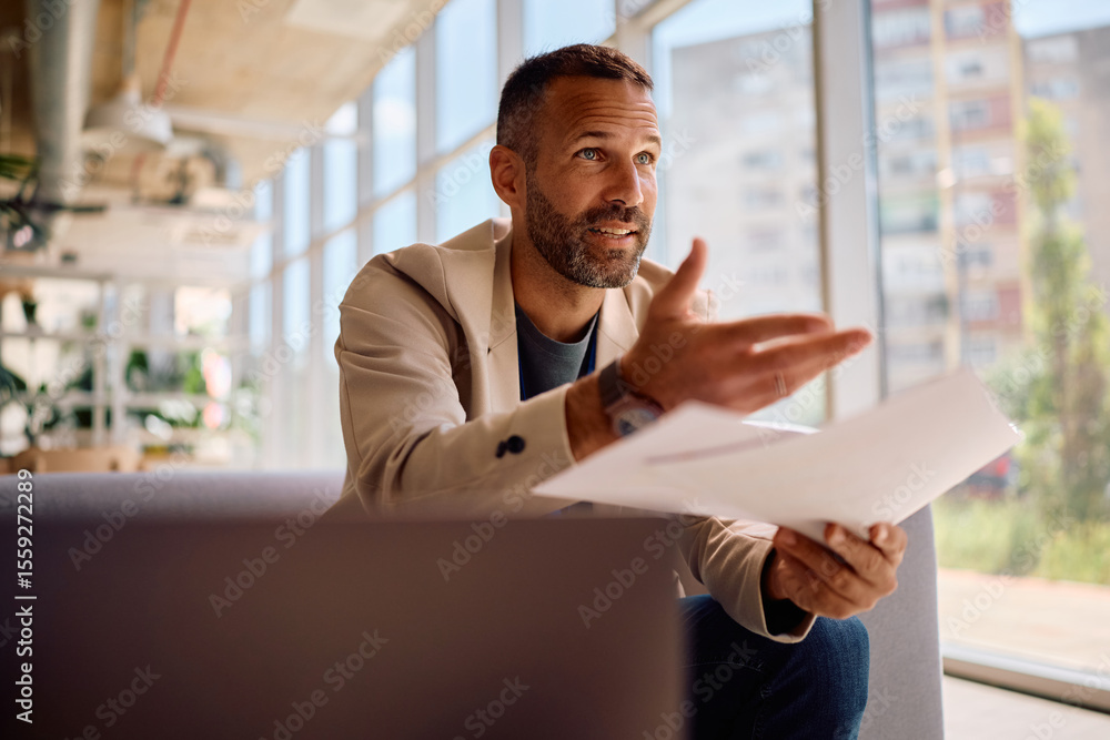Fototapeta premium Male entrepreneur talking while analyzing business reports in the office.