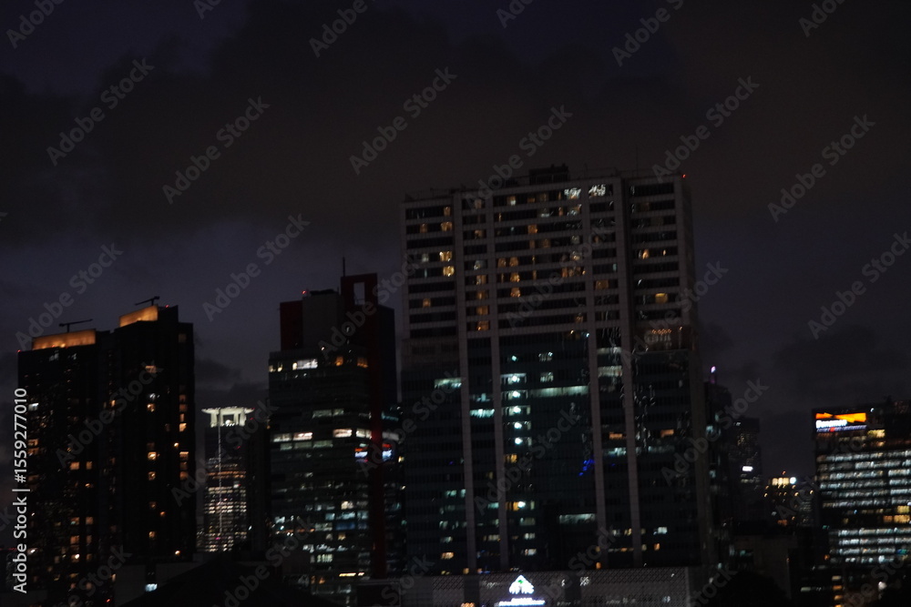 Obraz premium Manila Skyline at Night: Illuminated Buildings Against a Dark Sky