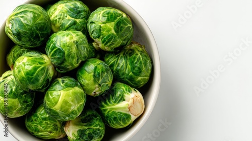 Fresh green Brussels sprouts arranged in a bowl on a white backdrop