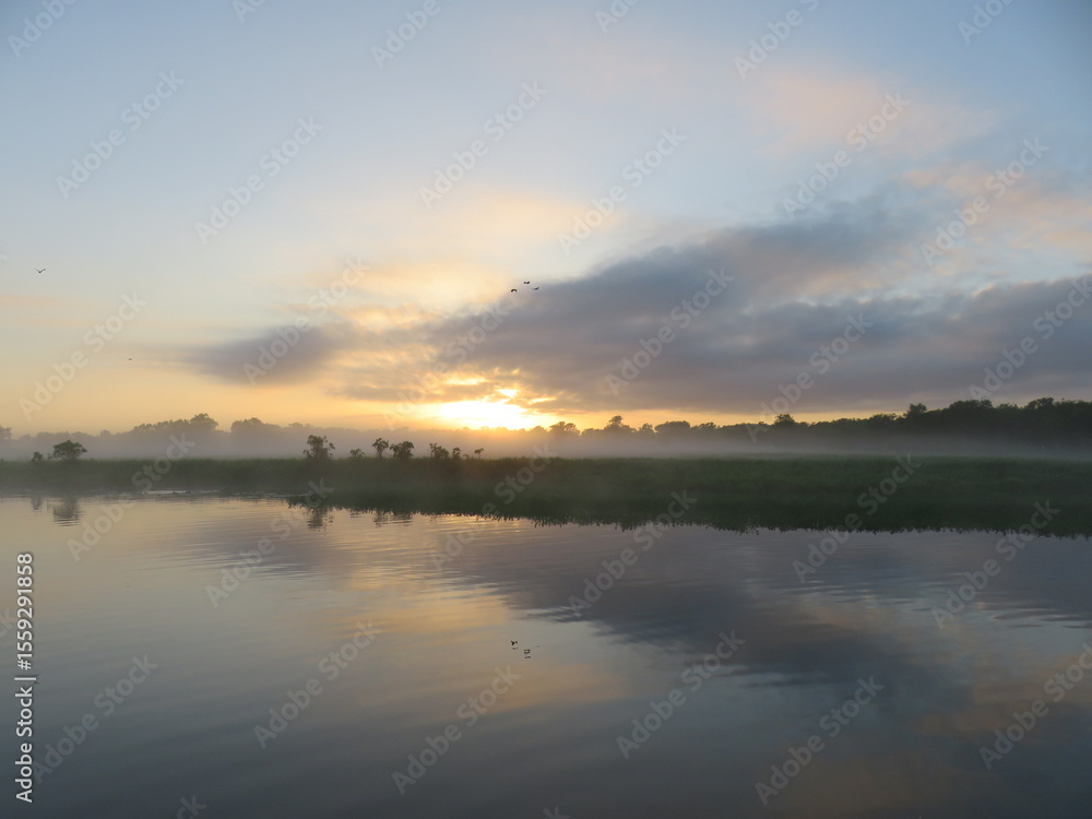 Fototapeta premium Sunrise with mist across still water