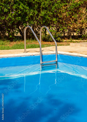 Metal pool ladder leading into calm turquoise water. Clean and minimal summer scene perfect for resort, holiday, spa, or wellness design themes.