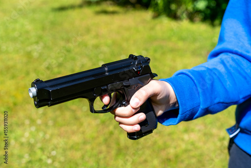 A toy pistol in the hands of a child.Dangerous gun games.A black pistol in his hand.