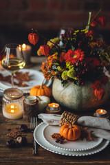 Elegant atmospheric beautiful dinner table setting for thanksgiving or wedding celebration, fall countryside style, pumpkins as decor. Romantic cozy home atmosphere. Wine, floral pumpkin centrepiece.