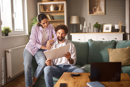 Canvas Print A couple sits on a couch in their living room, engaged in a discussion about life insurance while reviewing documents