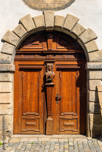 Summer cityscape - view of an antique wooden carved entrance door on Latran street in the historical center of Cesky Krumlov, Czech Republic