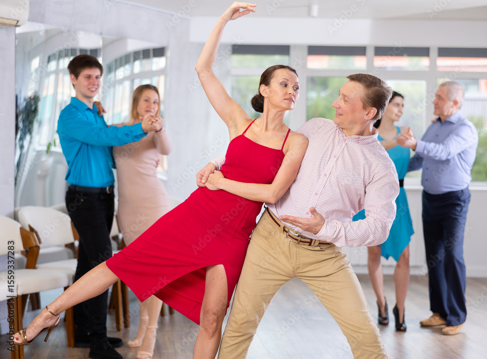 Fototapeta premium Positive young adult woman learning to dance Viennese waltz with male partner in choreography class, performing elegant support..
