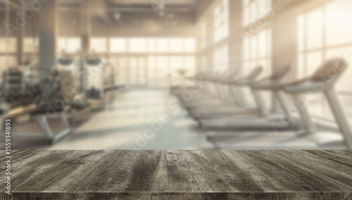 фотографія Rustic wooden worktop or tabletop with blurred background of a modern gym featuring treadmills and fitness equipment