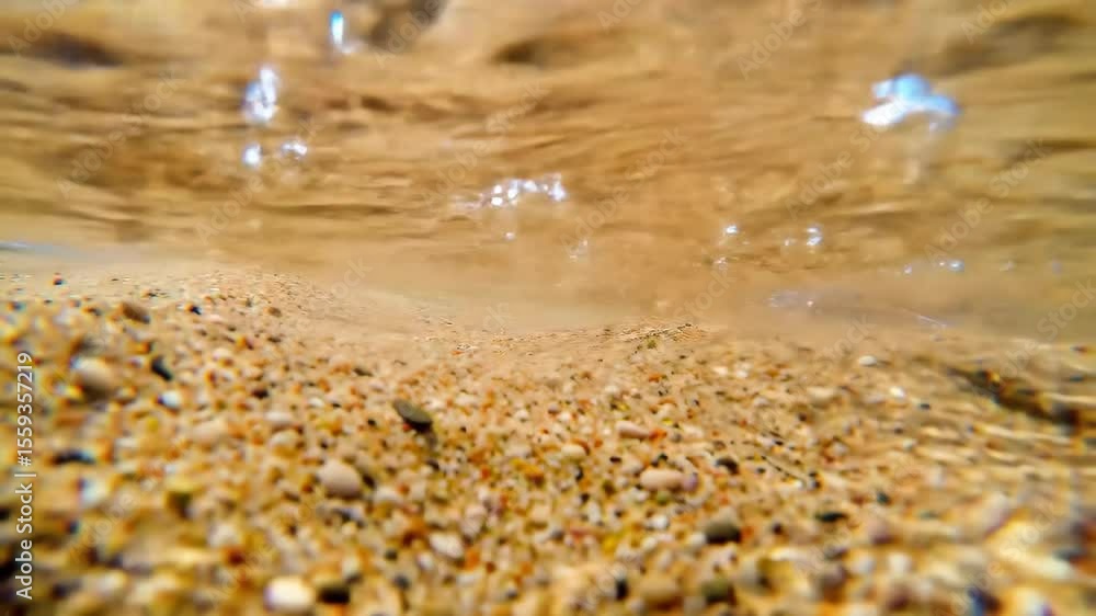 Underwater View of Sandy Beach with Pebbles and Rippling Water Underwater View of Sandy Beach with Pebbles and Rippling Water