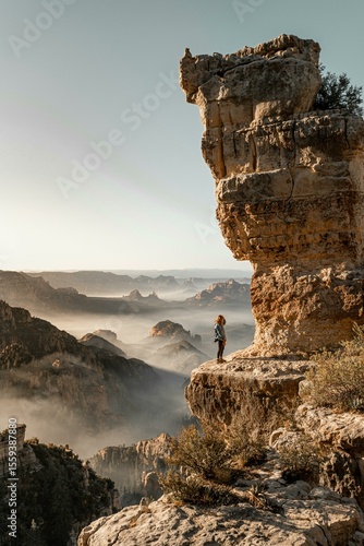 Adventurer Standing on Rocky Cliff Edge Above Majestic Canyon at Sunrise